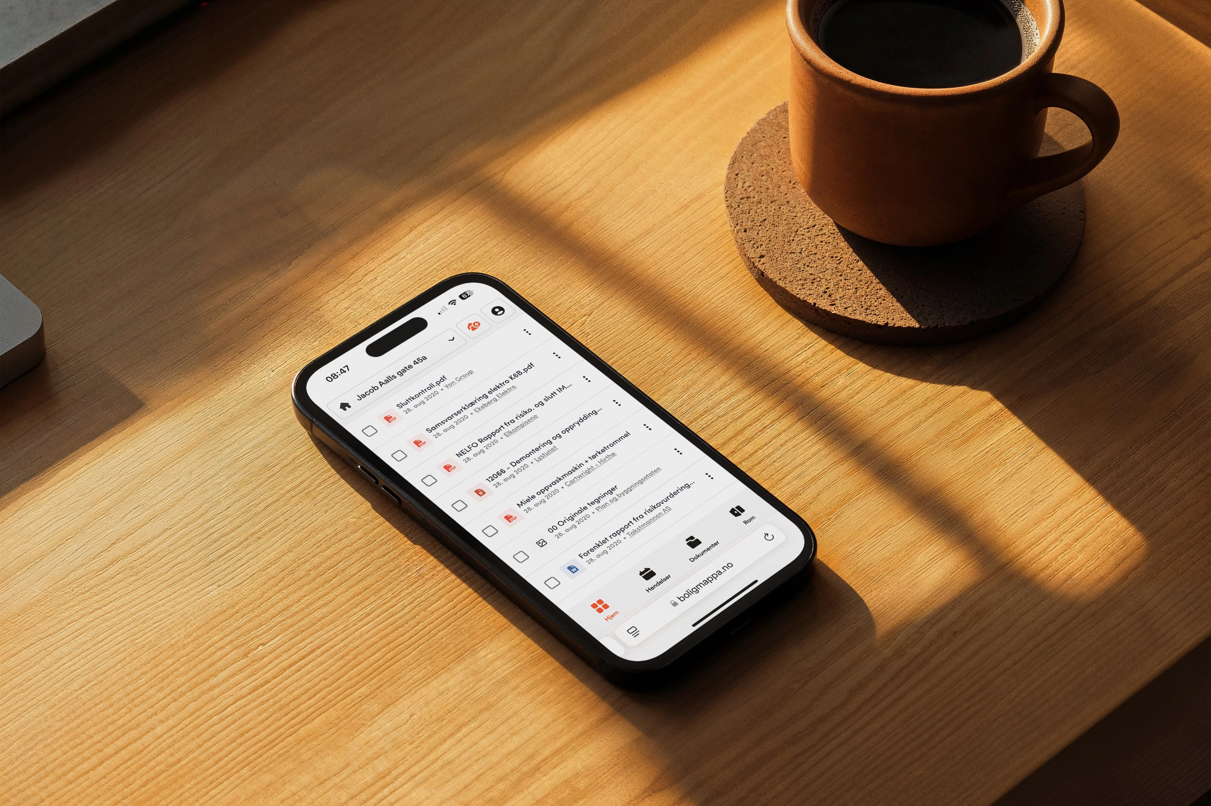 Boligmappa — home documentation on a phone beside a cup of coffee